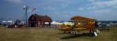 A yellow Boeing A75N1, not far from the barn